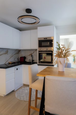 Eine moderne Küche mit weißen Schränken, einem Holzesstisch und einem Blumentopf.