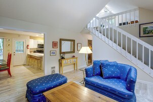 Una sala de estar con un sofá azul, una mesa de centro de madera y una escalera.