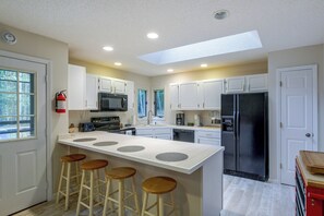 A modern kitchen with white cabinetry, a central island with stools, a stainless steel refrigerator, and a skylight. - 2 Mi to Beech Mtn Resort Lifts: Family Home (Banner Elk)