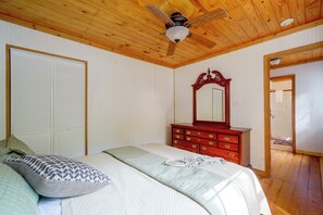 Un dormitorio con cama, cómoda, ventilador de techo y puerta.