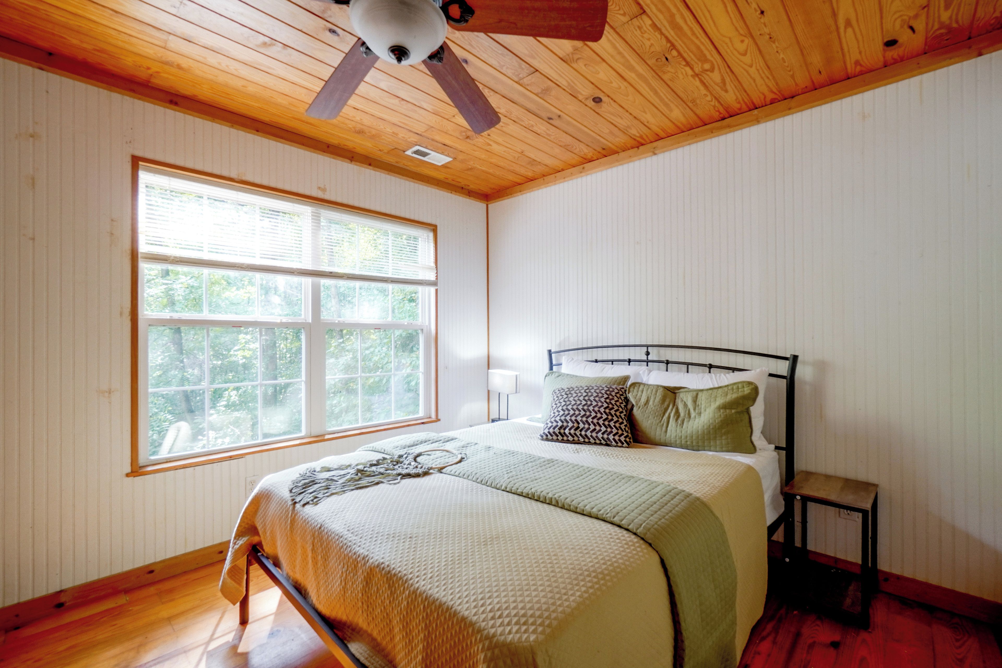 Un dormitorio con cama, ventana y ventilador de techo.
