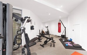 A gym with various exercise equipment, including a treadmill, weight bench, and kettlebells. - The Chetwynd Elegant West Melbourne Hideaway (West Melbourne)