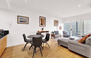 A modern living space with a dining area, a sofa, and a balcony with a view. - The Chetwynd Elegant West Melbourne Hideaway (West Melbourne)
