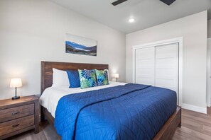 Quarto com cama, mesas de cabeceira, quadro na parede e guarda-roupa.