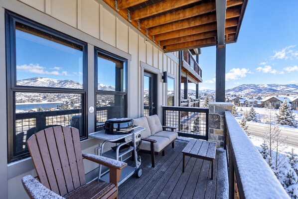 Une terrasse en bois avec un espace salon, un barbecue et une vue sur un paysage enneigé.