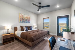Ein Schlafzimmer mit einem Bett, Nachttischen, einem Deckenventilator, einem Fenster mit Aussicht und einer Essecke mit Tisch und Stühlen.