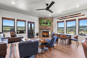 Uma sala de estar espaçosa com lareira, assentos confortáveis e grandes janelas com vista para o exterior.