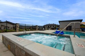 Ein Bereich mit Whirlpool, Schwimmbad, Liegestühlen und einer umzäunten Terrasse.