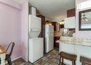 A compact kitchen with a refrigerator, stove, and sink. - The Summit 1028 (Panama City Beach)