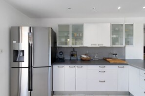 Eine moderne Küche mit Edelstahlgeräten, weißen Schränken und einer Arbeitsplatte mit verschiedenen Gegenständen.