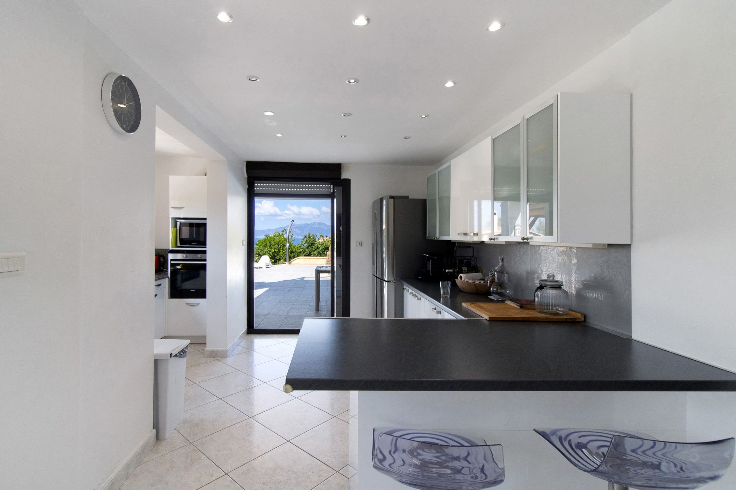 A modern kitchen with a black countertop, stainless steel appliances, and a view of the outdoors.