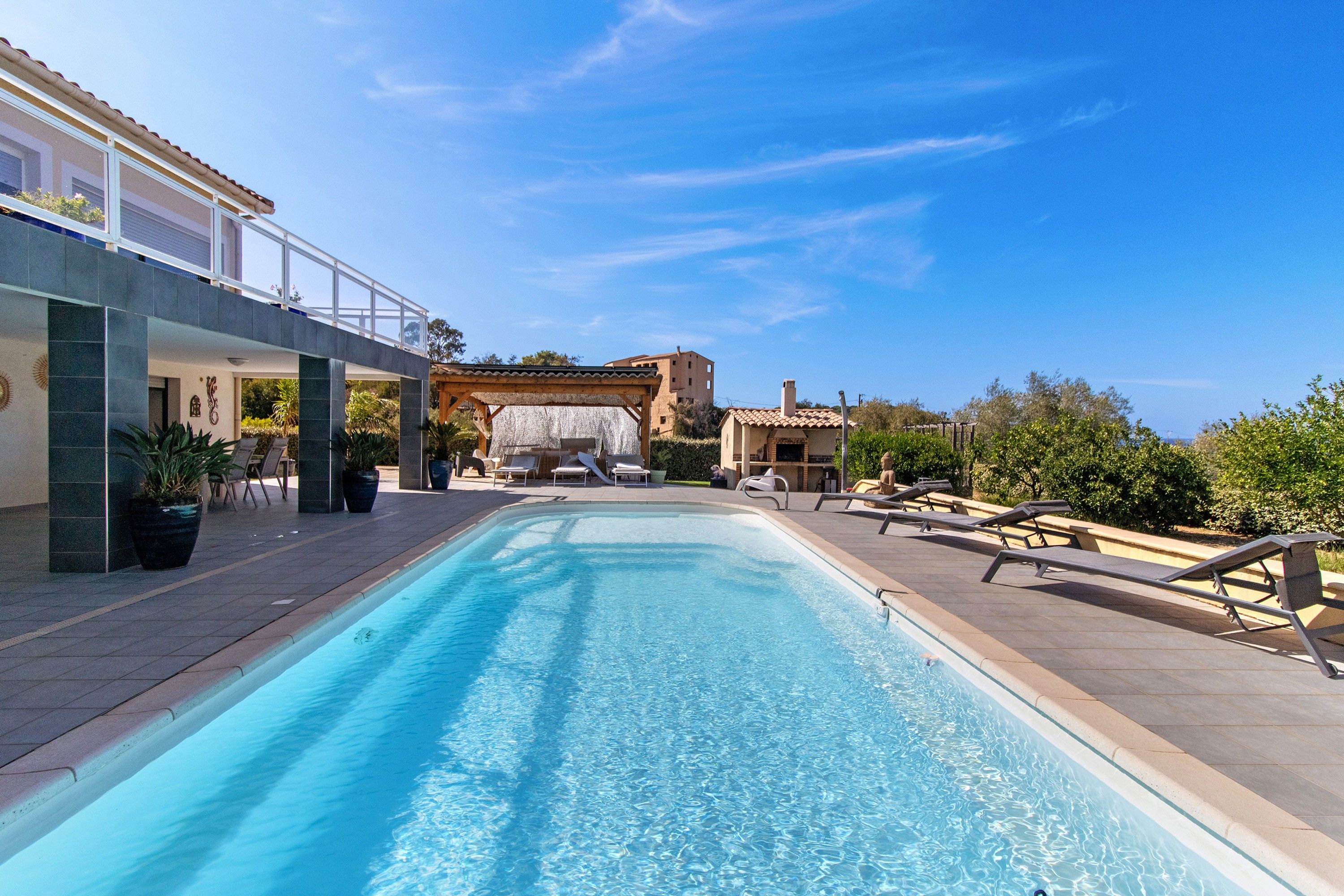 A swimming pool with lounge chairs and a pergola structure.