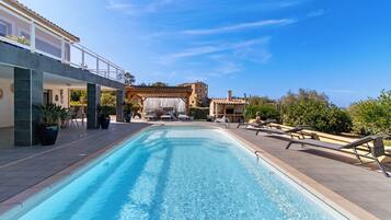 A swimming pool with lounge chairs and a pergola structure.