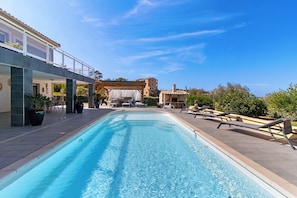 A swimming pool with lounge chairs and a pergola structure.