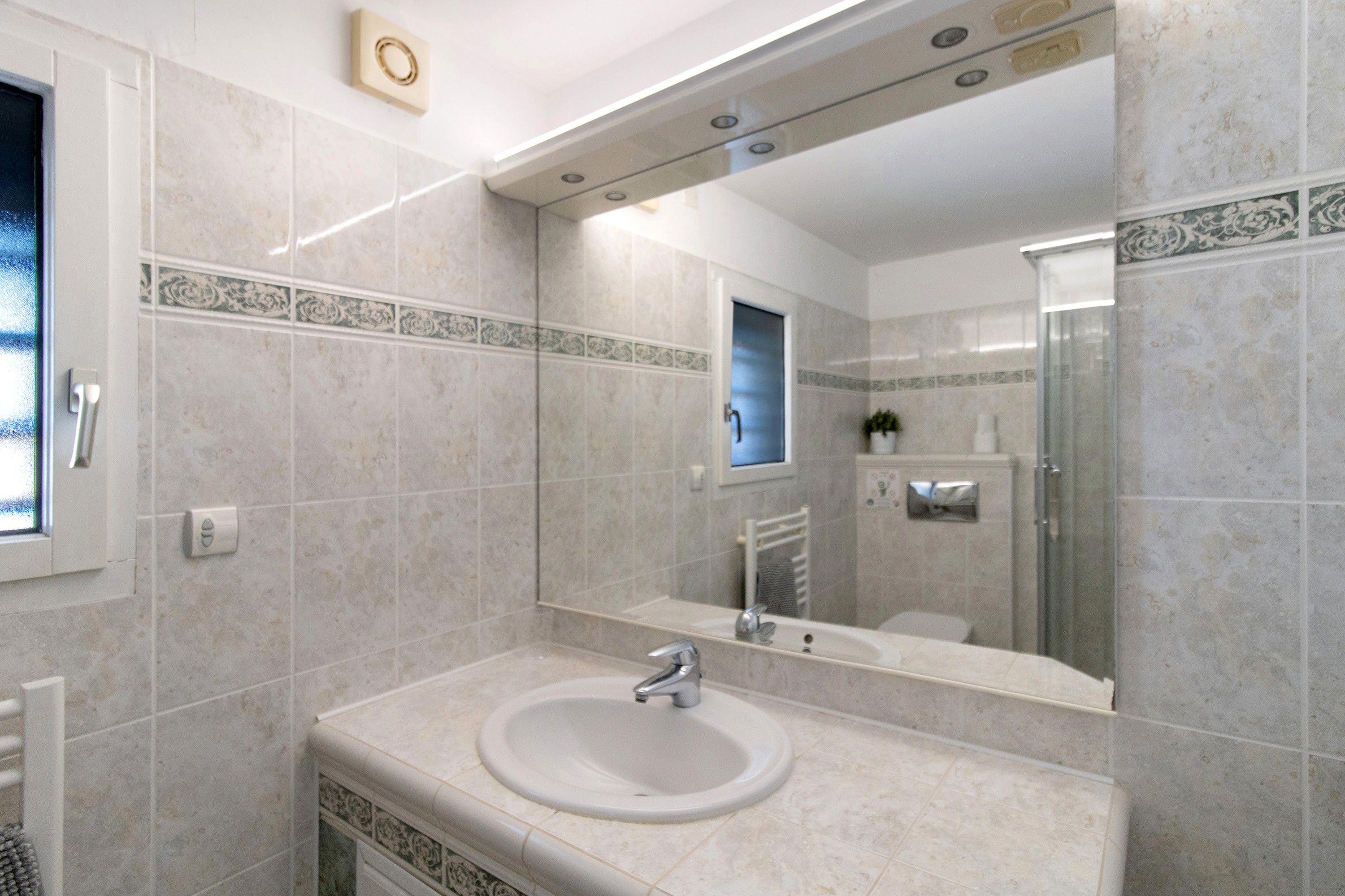 Une salle de bain avec un lavabo, un miroir et une douche.