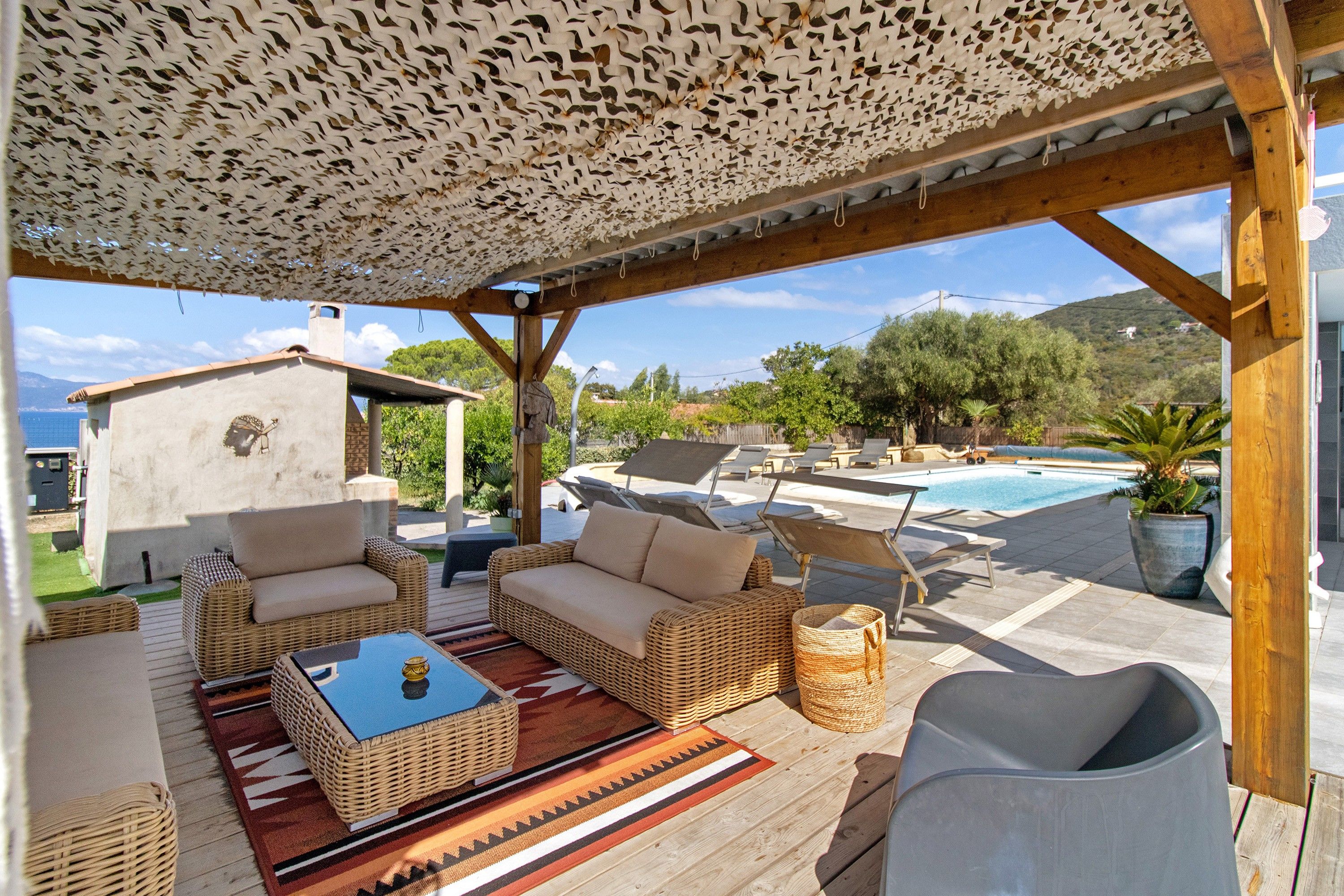 Eine Terrasse im Freien mit Korbmöbeln, einem Pool und Meerblick.
