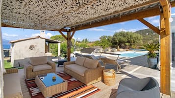 Eine Terrasse im Freien mit Korbmöbeln, einem Pool und Meerblick.