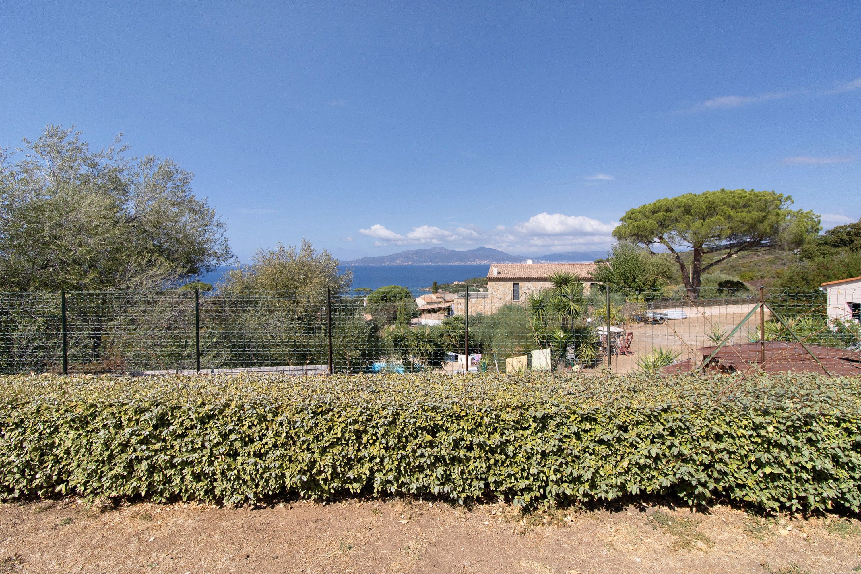 A fenced property with a view of the sea and mountains.