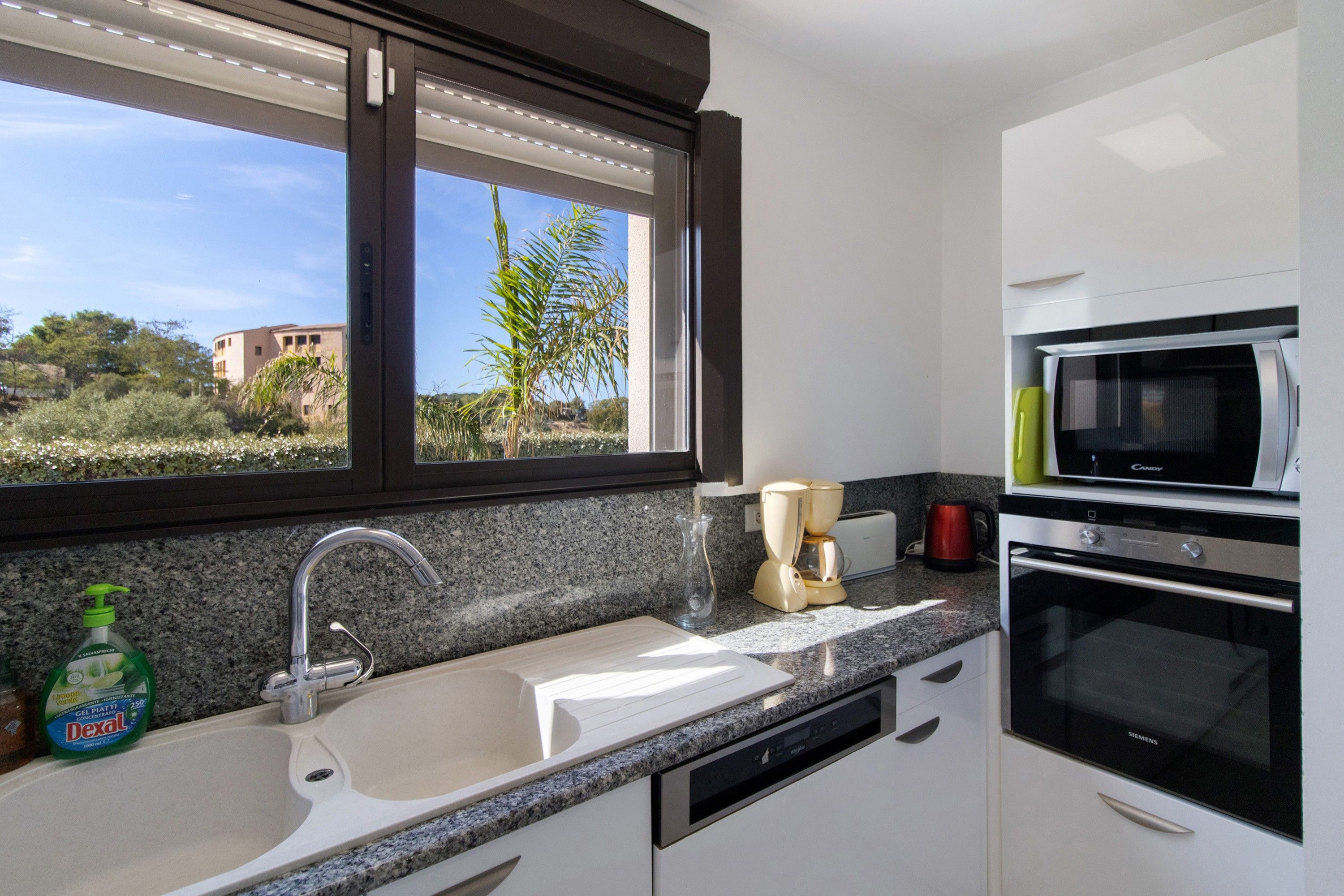 A modern kitchen with a sink, dishwasher, microwave, and oven.