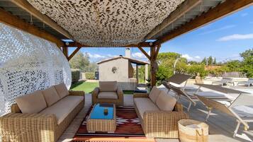 A covered outdoor seating area with wicker furniture and a patterned rug.