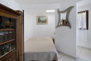 Ein Schlafzimmer mit einem Bett, einem Holzschrank mit Glastüren, einem Gemälde an der Wand und einem Spiegel.