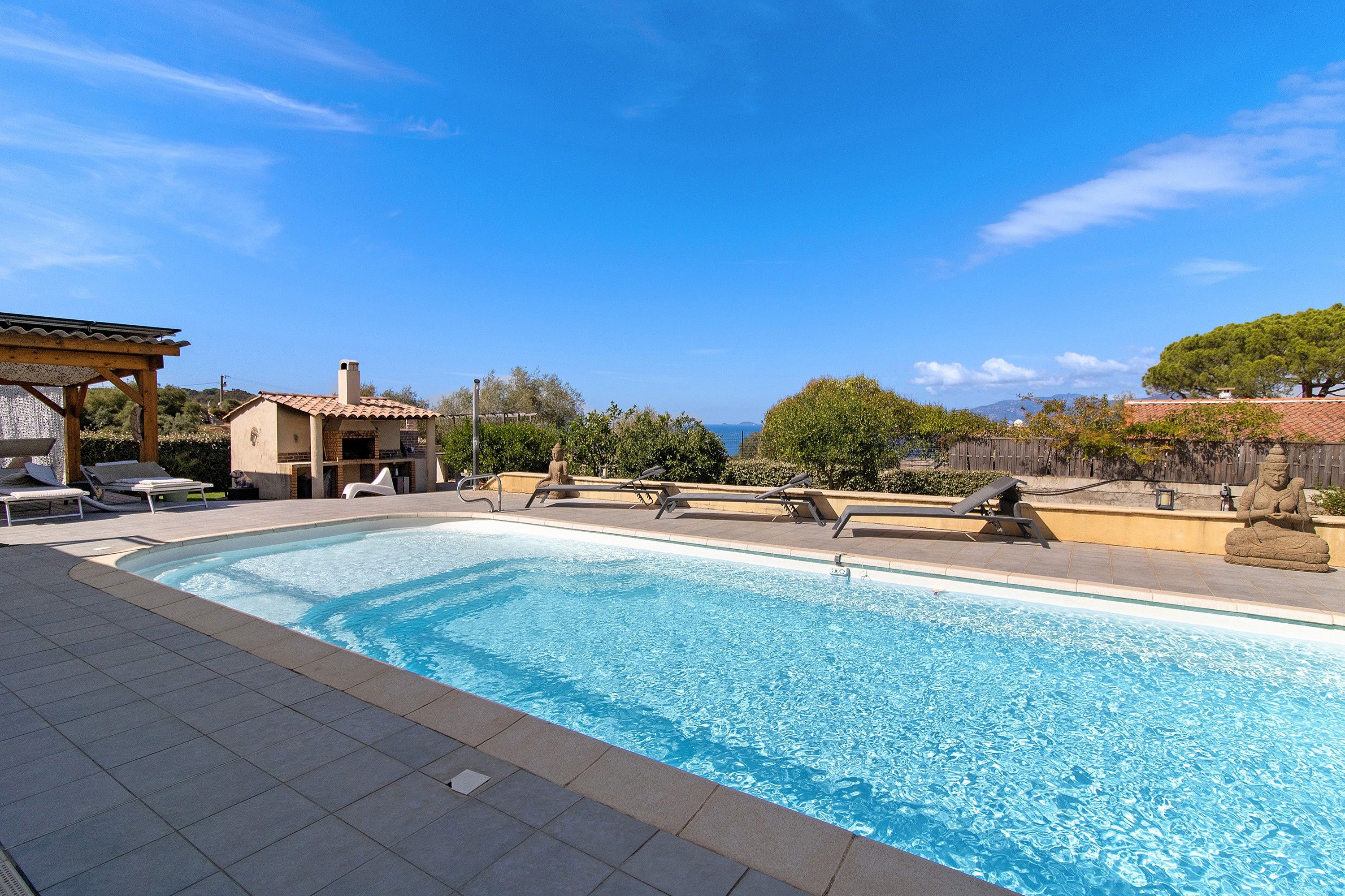 Une piscine avec des chaises longues et une pergola.