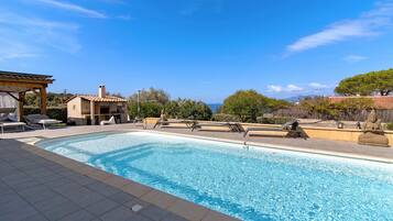Une piscine avec des chaises longues et une pergola.