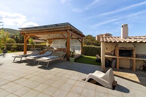 Un patio con sillones de descanso, una pérgola y un horno de ladrillo.