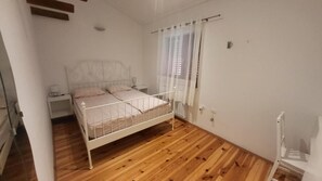 Une chambre avec un lit simple, une table de chevet, une chaise et une fenêtre avec des rideaux.