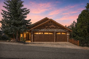 A two-story log cabin with a stone foundation, a stone chimney, and a garage with two doors. - Starry Night, Lake Views, Hot Tub, Mins 2 Lake (Big Bear Lake)