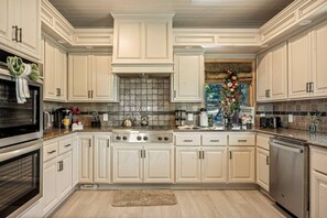 A spacious kitchen with white cabinetry, a central island, stainless steel appliances, and a decorative vase on the countertop. - Starry Night, Lake Views, Hot Tub, Mins 2 Lake (Big Bear Lake)
