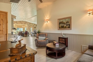 A spacious lobby with a high ceiling, a stone wall, a fireplace, and a dining area in the background. - Starry Night, Lake Views, Hot Tub, Mins 2 Lake (Big Bear Lake)