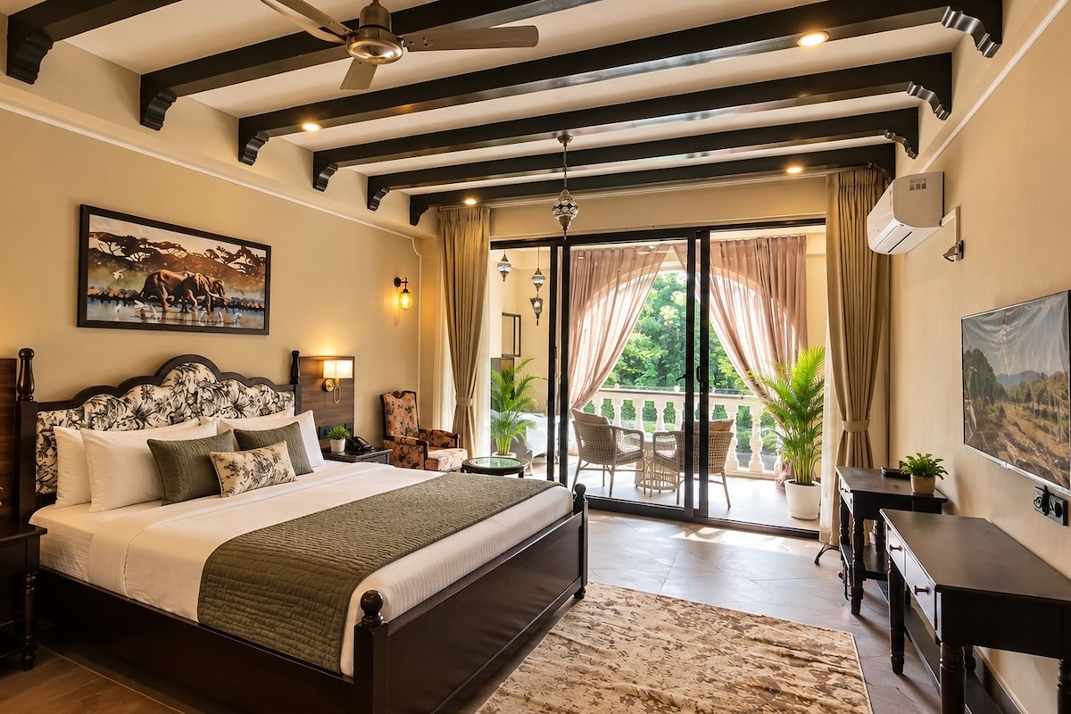 Quarto com cama grande, ventoinha no teto, televisão e varanda com cortinas.