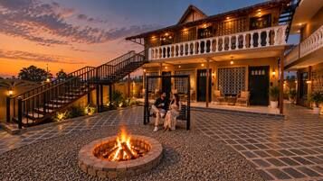 A two-story building with a fire pit in the center, outdoor seating, and a staircase leading to the upper level.