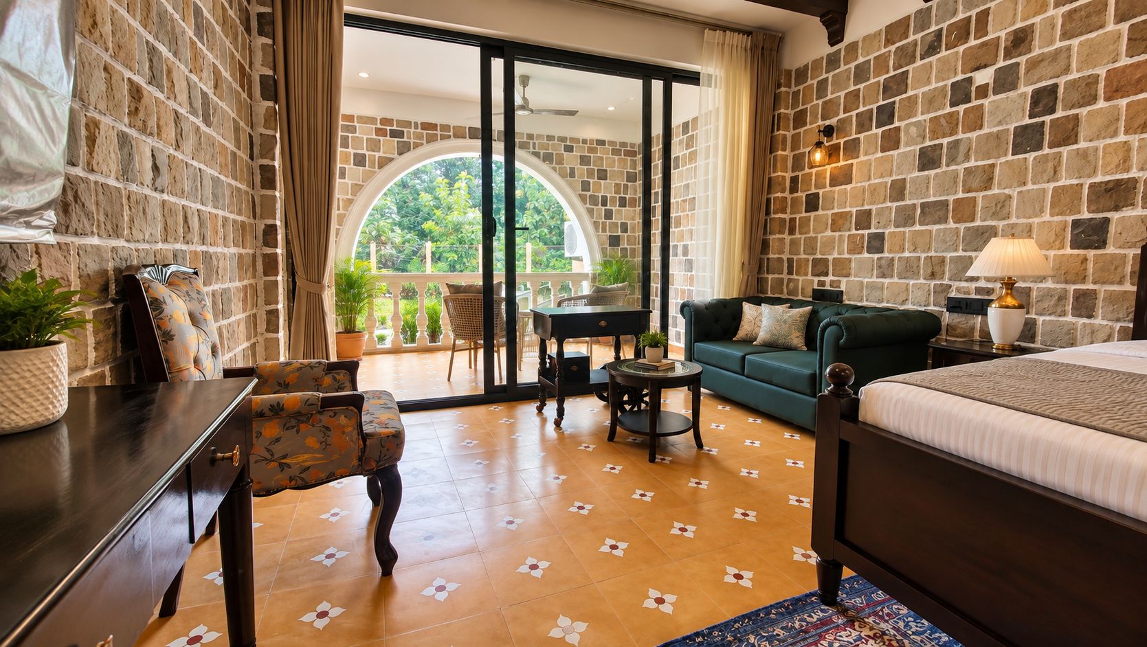 Habitación de hotel con cama, sofá, escritorio y vistas al exterior a través de un ventanal.