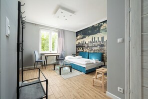Un dormitorio moderno con un mural de paisaje urbano, una cama, un escritorio y una silla.