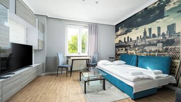 Ein modernes Schlafzimmer mit Stadtbild-Wandgemälde, einem großen Bett, einem Fernseher und einem Essbereich.