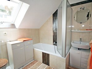 A bathroom with a bathtub, a shower, a sink, and a mirror. - Holiday Apartment With 2 Bedrooms (Schramberg)