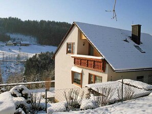 A two-story house with a balcony, surrounded by snow-covered landscape and trees. - Holiday Apartment With 2 Bedrooms (Schramberg)