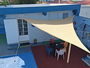 A blue building with a white door, a table with chairs, and a hanging light fixture. - Cozy Aparment 2 Bedroom Near THE Best Beaches IN Boqueron Puerto Rico (Cabo Rojo)