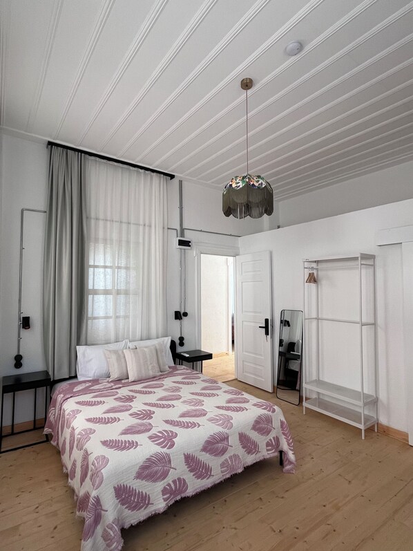 Un dormitorio con cama, mesita de noche, espejo, armario e iluminación en el techo.