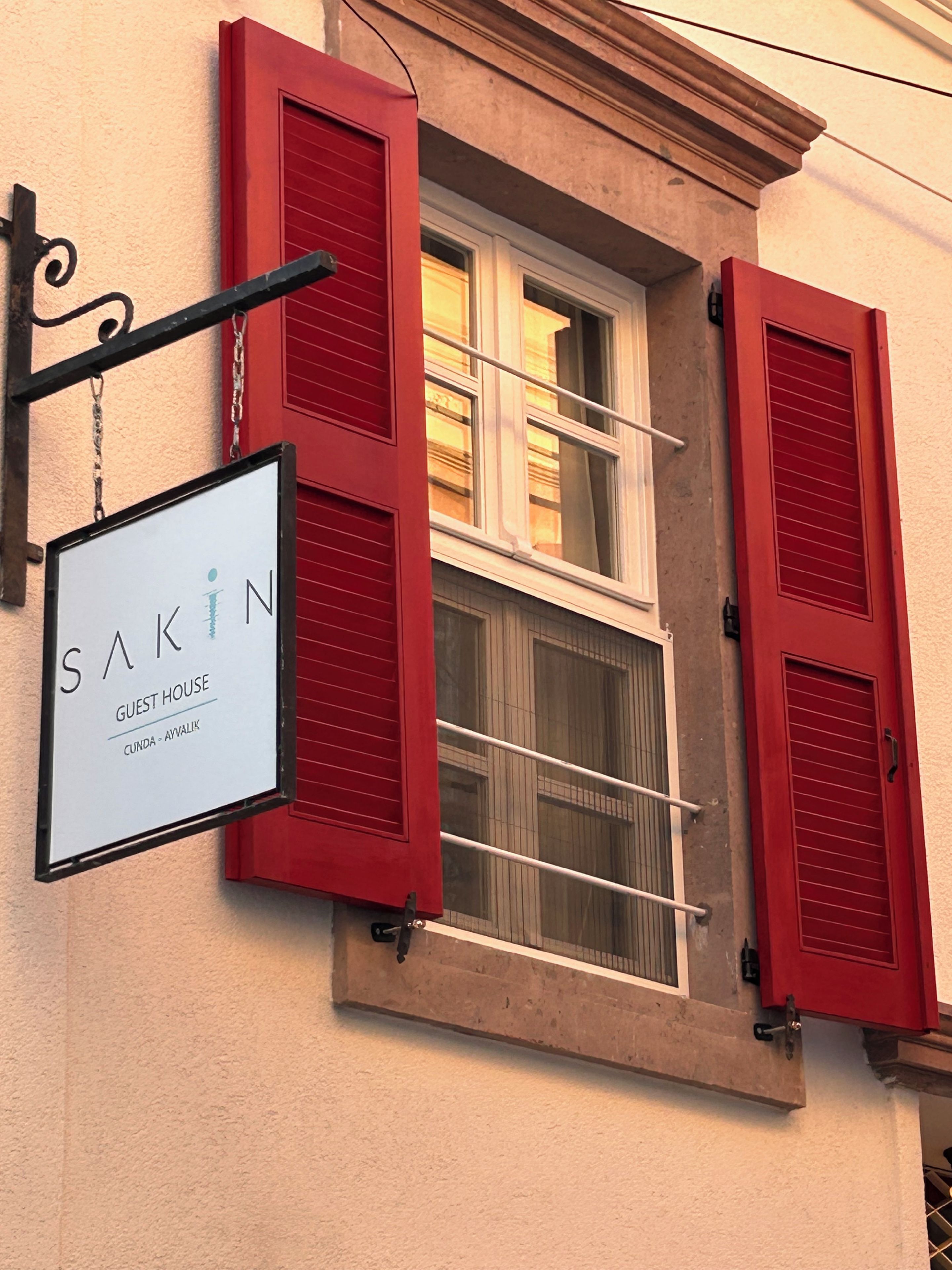A building with a sign that reads 'SAKIN GUEST HOUSE CUNDA - AYVALIK.'
