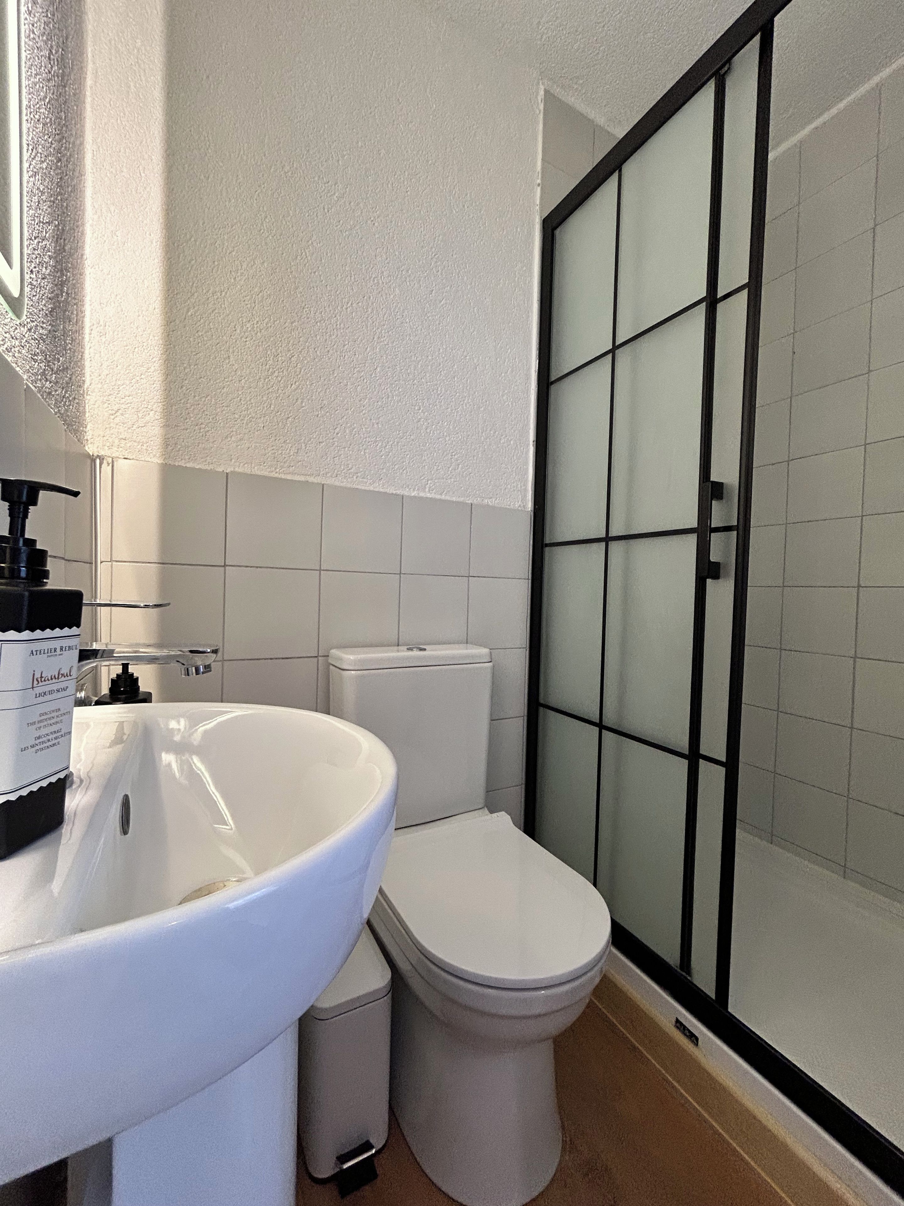 Ein Badezimmer mit weißem Waschbecken, einer Toilette und einer Duschkabine.