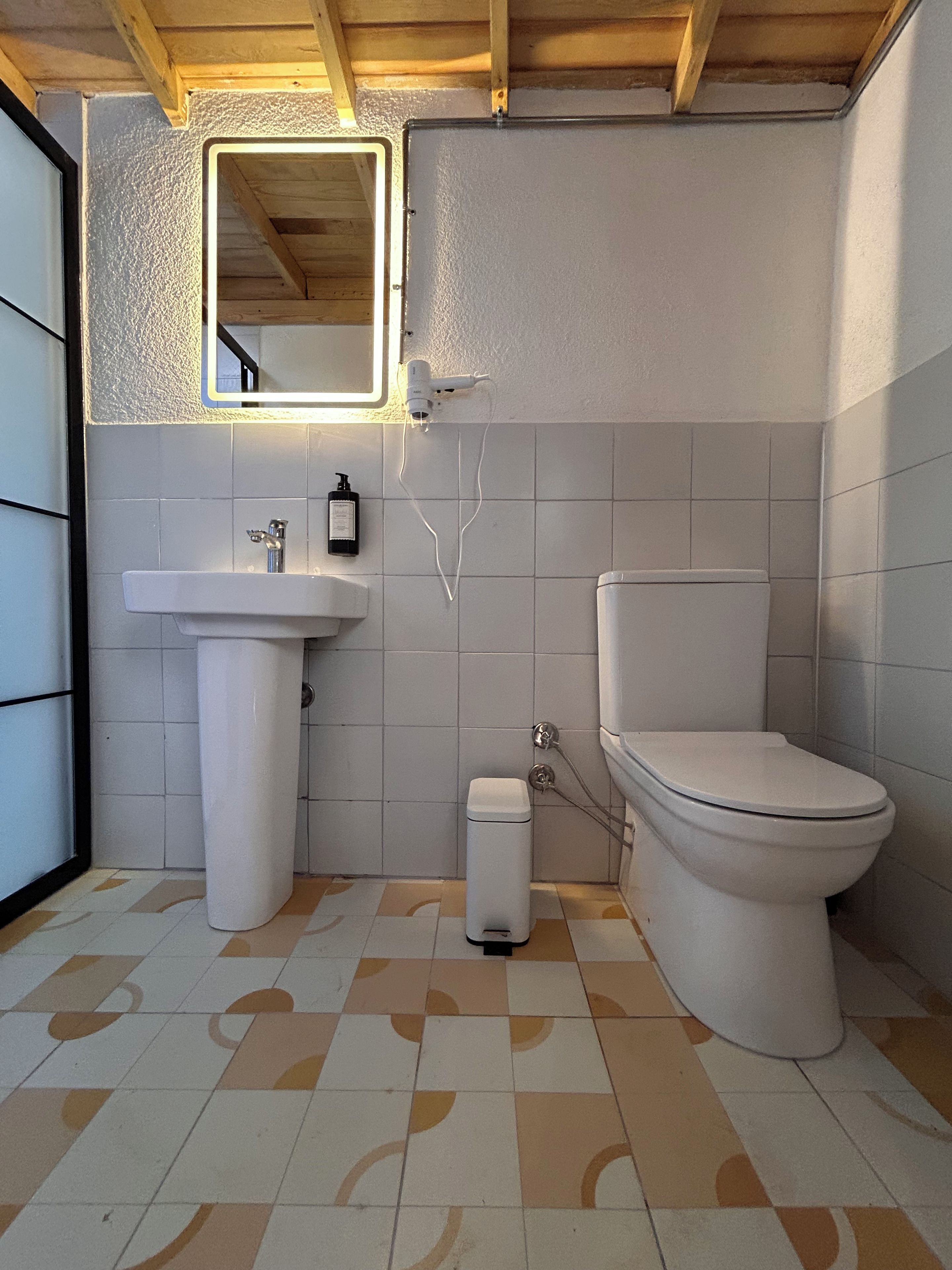 A bathroom with a white sink, a toilet, and a mirror.