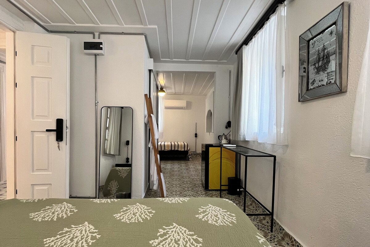 Una camera d'albergo con un letto, una scrivania, una sedia, uno specchio e un quadro appeso al muro.