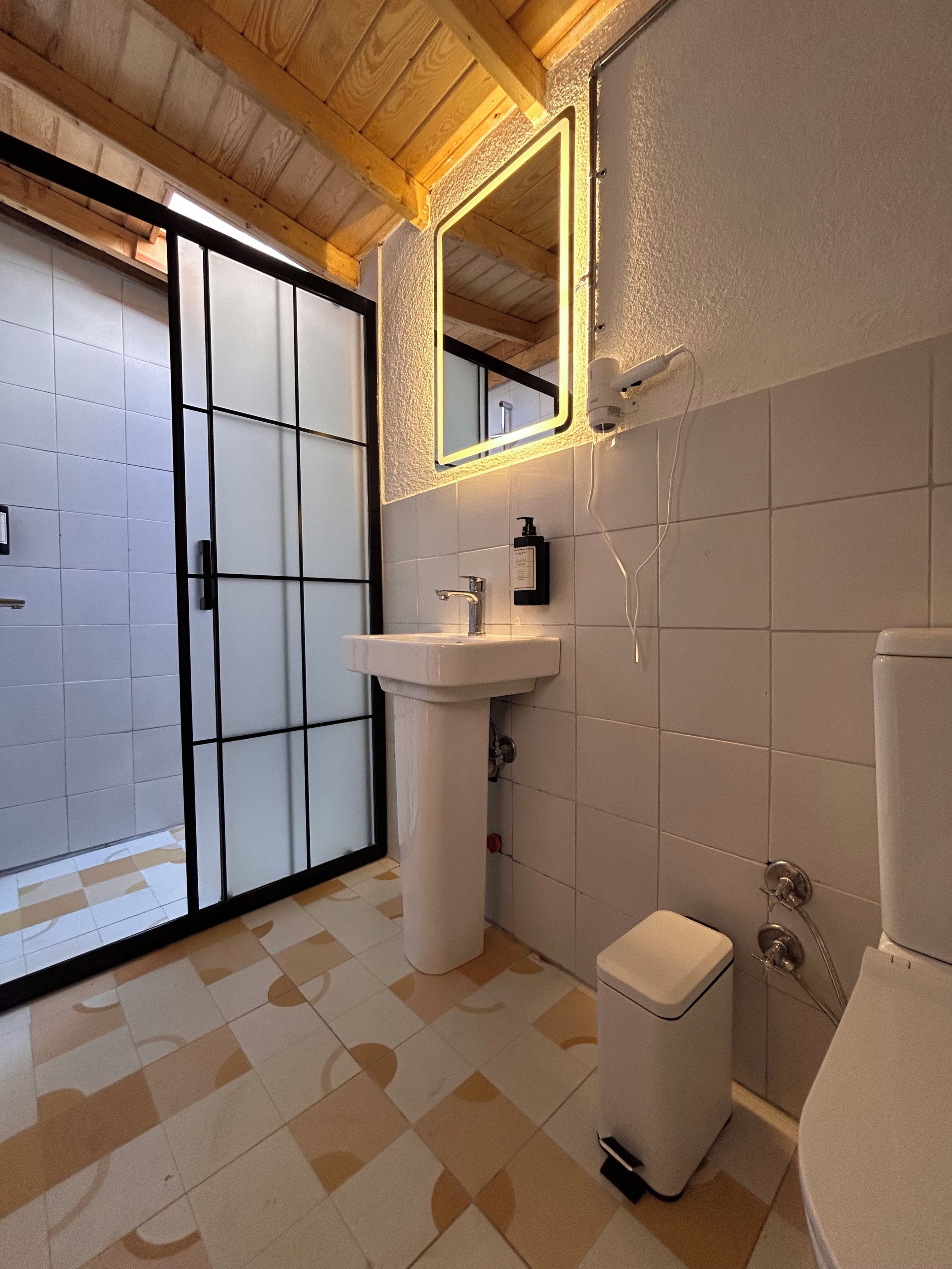 A bathroom with a sink, toilet, and a mirror with a light.