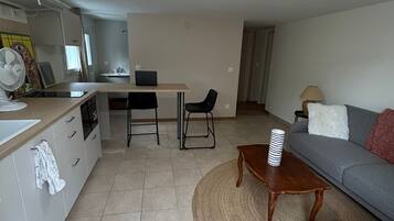 A modern living room with a sofa, a coffee table, and a dining area with a table and chairs.