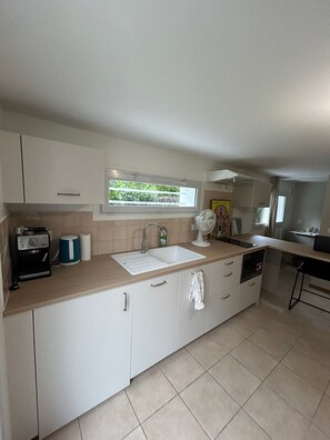 A modern kitchen with a sink, a coffee machine, and a window with a view of greenery.