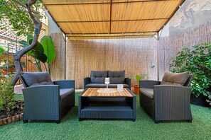 Un espace extérieur aménagé avec des meubles en osier, une table centrale et un décor de bambous.