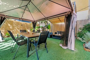 Eine Außenpatio mit Tisch, Stühlen, einer Couch und einer hängenden Lampe.
